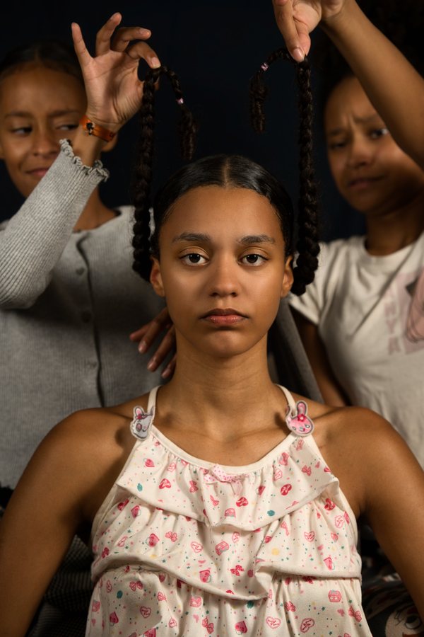 Deux sœurs soulèvent les tresses d'une adolescente impassible