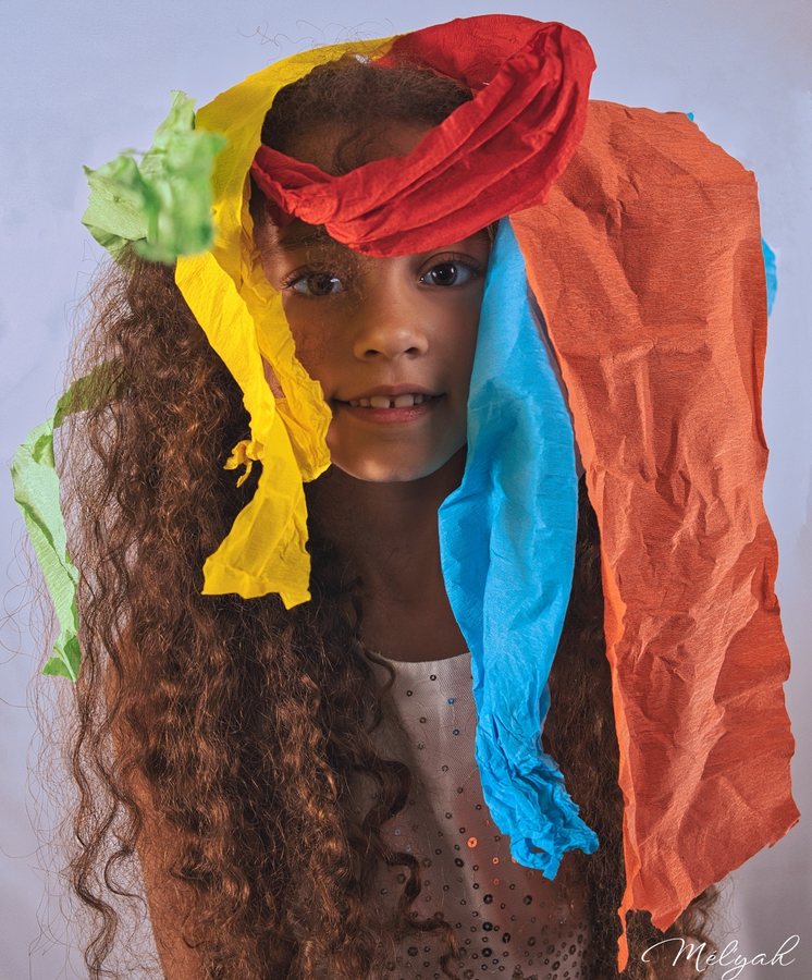 Fillette souriante, la tête couverte de rubans de papier crépon multicolores