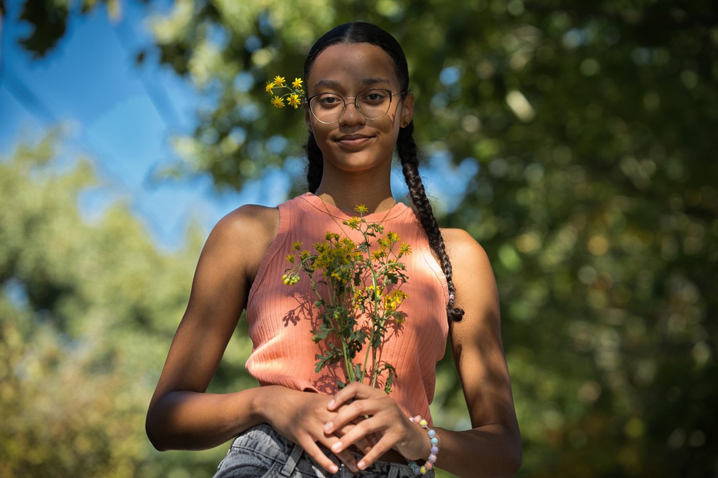 Jeune fille aux tresses tenant des fleurs jaunes